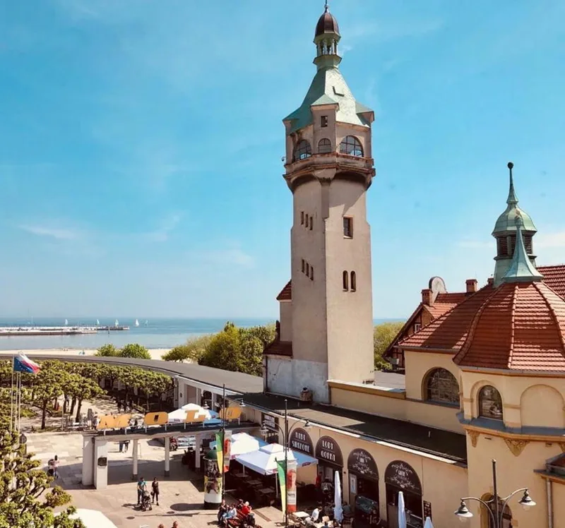 Sopocka latarnia i zabytkowa zabudowa przy plaży.